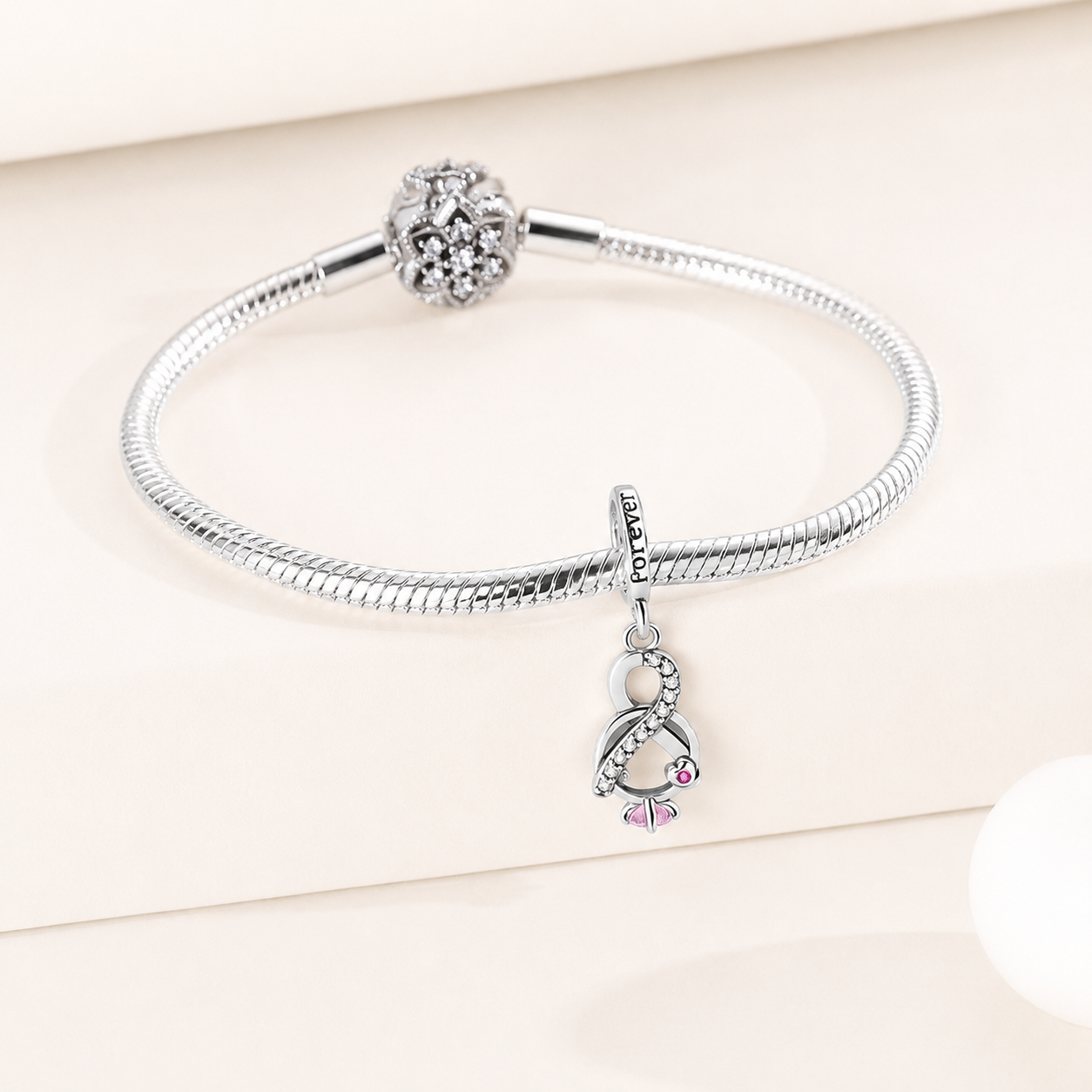 Side view of the infinity knot dangle charm highlighting zirconia accents and polished silver finish | Asttery