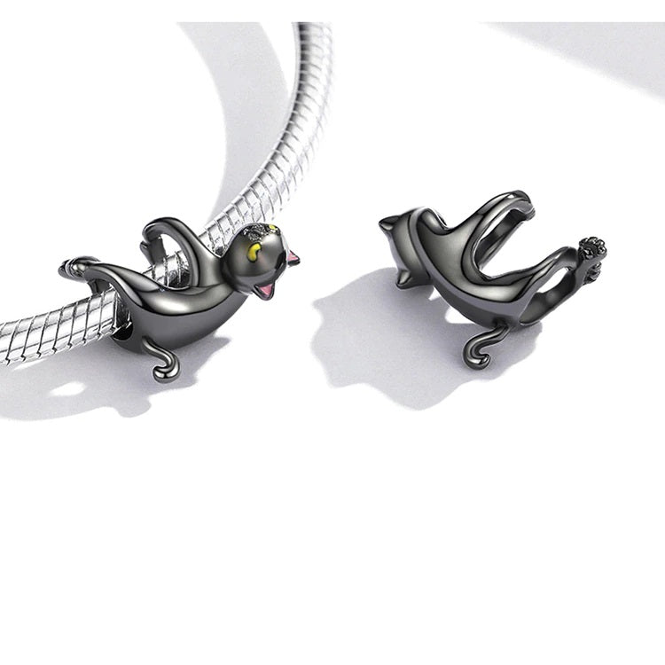 Stylized cat-shaped charm, silver 925 with curved tail and fluid posture, black enamel finish with yellow and pink accents, Asttery