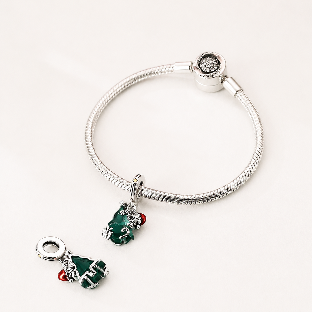 This charm tells the story of a joyful figure enveloped around a radiant green tree, as if safeguarding the gentle magic that only Christmas can bring | Asttery