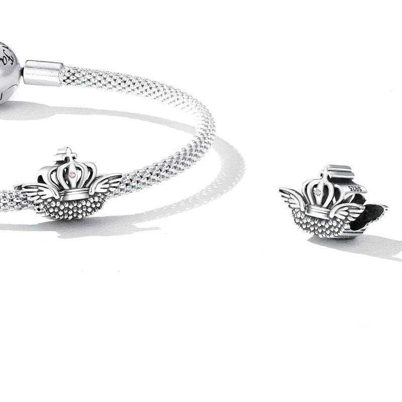 Winged silver crown charm with feathered texture and a soft pink stone at the center |Asttery